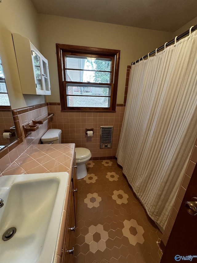 bathroom featuring sink, heating unit, tile walls, and toilet