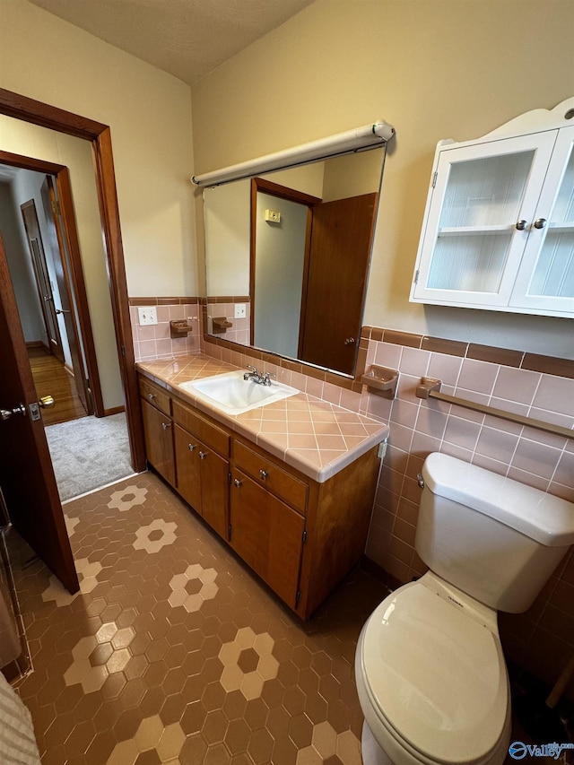 bathroom featuring vanity, toilet, and tile walls