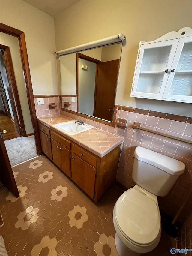 bathroom with vanity, toilet, and tile walls