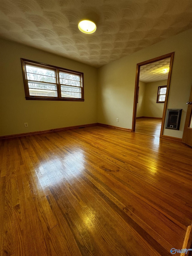 unfurnished room featuring heating unit and light wood-type flooring