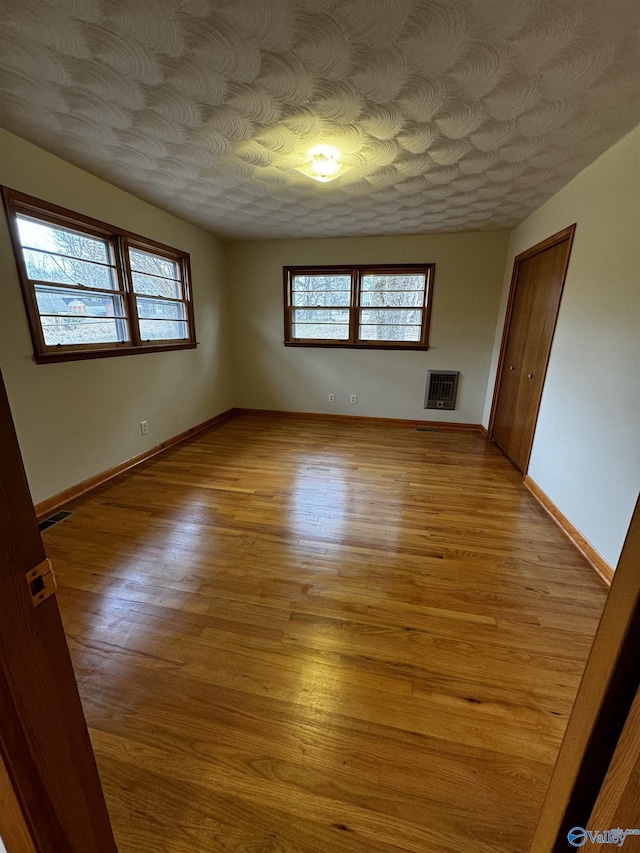 empty room with heating unit and light hardwood / wood-style flooring