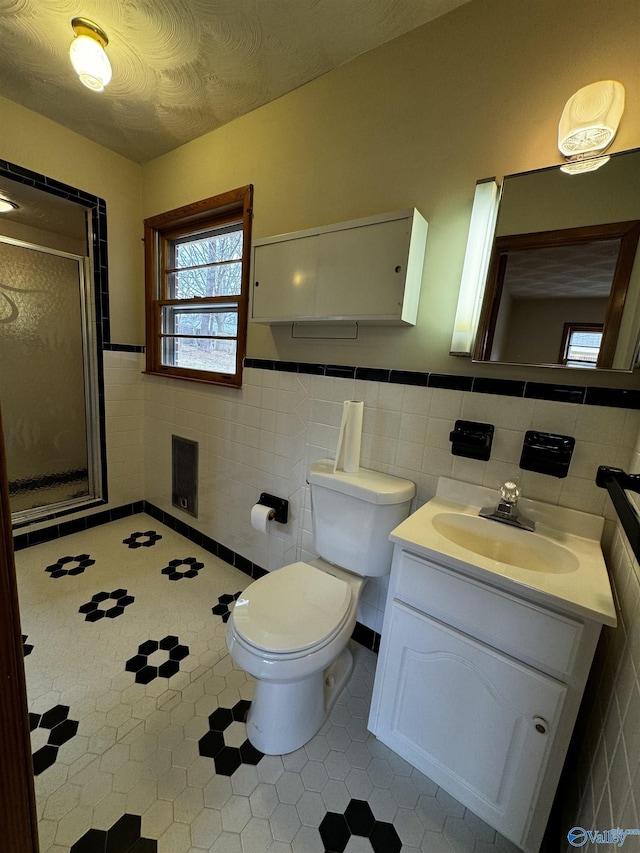 bathroom featuring vanity, toilet, an enclosed shower, and tile walls