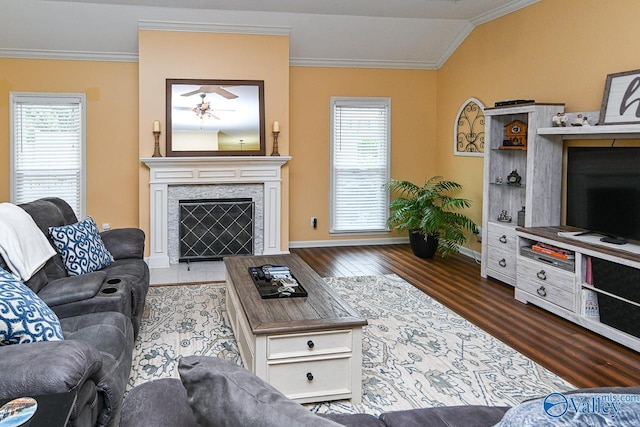 living room with crown molding, a tile fireplace, wood finished floors, and baseboards