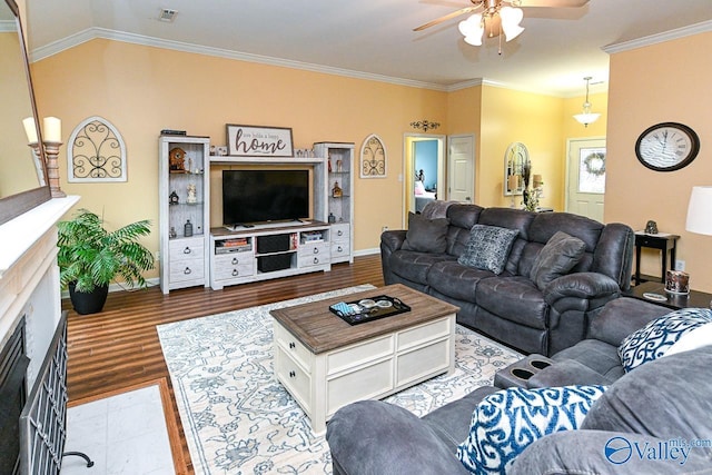 living room with wood finished floors, ceiling fan, crown molding, and baseboards
