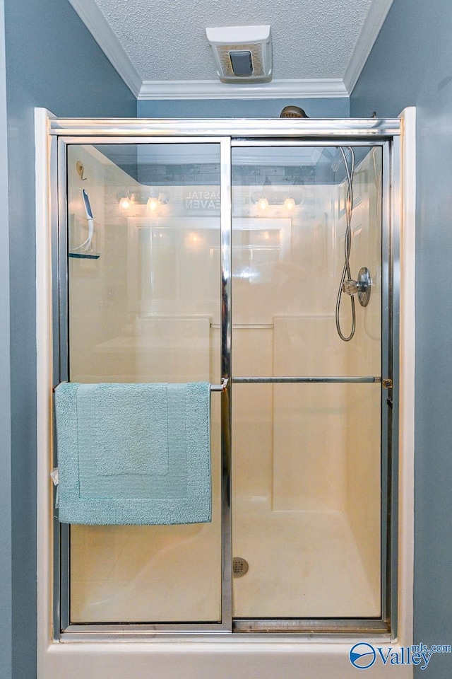 bathroom with crown molding, a textured ceiling, and a shower stall
