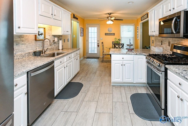 kitchen featuring a sink, a peninsula, stainless steel appliances, and white cabinetry