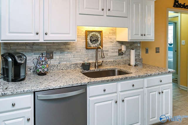 kitchen with white cabinets, stainless steel dishwasher, backsplash, and a sink