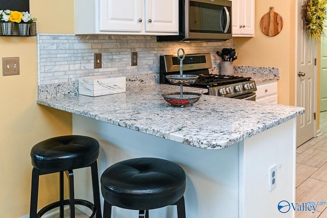 kitchen featuring appliances with stainless steel finishes, a kitchen bar, and tasteful backsplash
