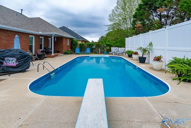 view of swimming pool with a diving board, a patio, a fenced in pool, and a fenced backyard