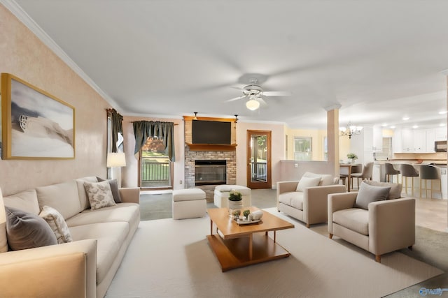 living room featuring crown molding, a stone fireplace, and ceiling fan with notable chandelier