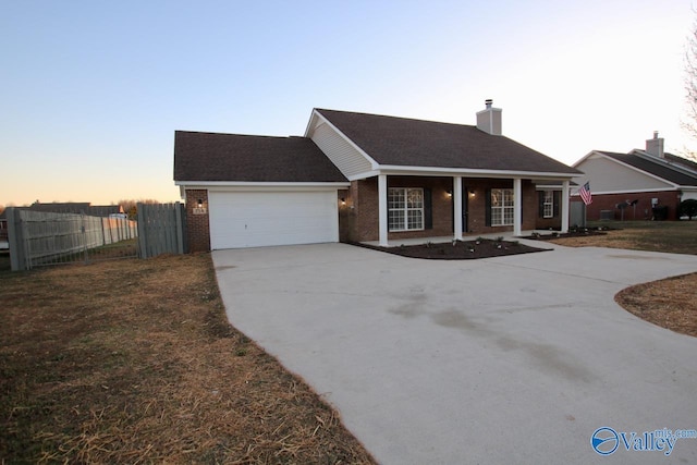 view of front of property featuring driveway, a garage, fence, and brick siding