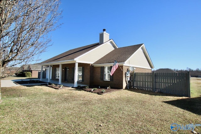 view of side of property featuring a yard, a chimney, fence, and brick siding