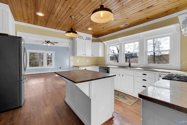 kitchen with appliances with stainless steel finishes, wood ceiling, a kitchen island, white cabinetry, and hanging light fixtures