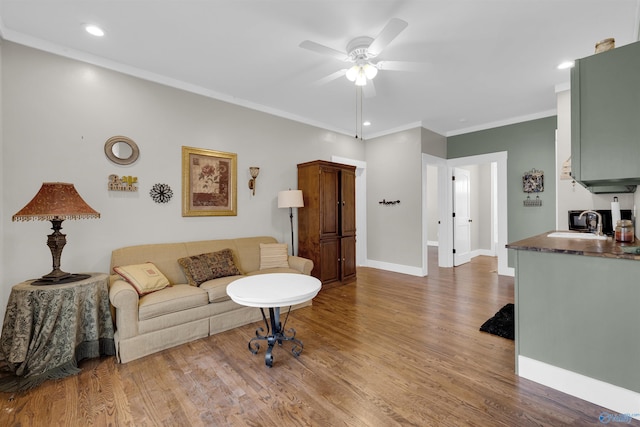 living room with crown molding, sink, ceiling fan, and wood-type flooring