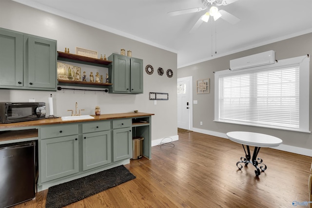 kitchen with a wall mounted air conditioner, wooden counters, sink, green cabinetry, and fridge