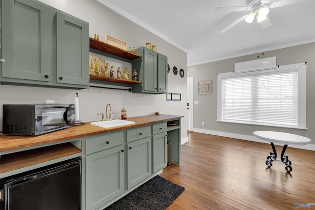 kitchen with butcher block counters, sink, an AC wall unit, and green cabinetry