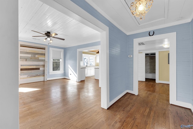 unfurnished living room with ornamental molding, ceiling fan, dark wood-type flooring, and wood walls