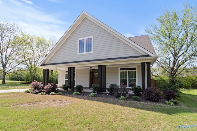 view of front of property featuring a front yard, a porch, and a shingled roof