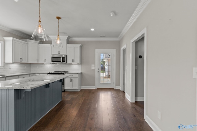 kitchen with white cabinets, light stone counters, appliances with stainless steel finishes, backsplash, and a breakfast bar area