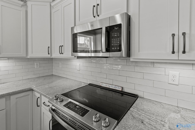 kitchen with white cabinetry, tasteful backsplash, appliances with stainless steel finishes, and light stone counters