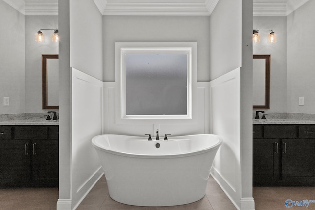 full bath with a freestanding bath, tile patterned flooring, crown molding, and two vanities