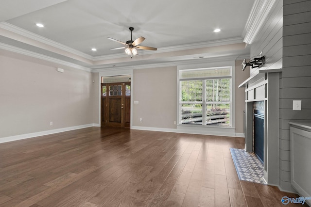 unfurnished living room with a fireplace with flush hearth, wood finished floors, ornamental molding, and a raised ceiling