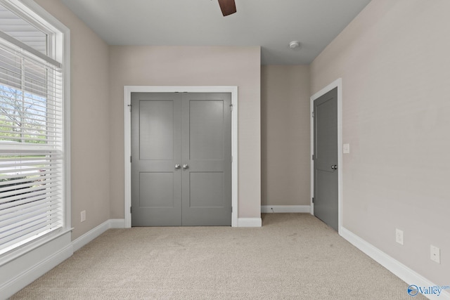 unfurnished bedroom featuring carpet floors, baseboards, a closet, and ceiling fan