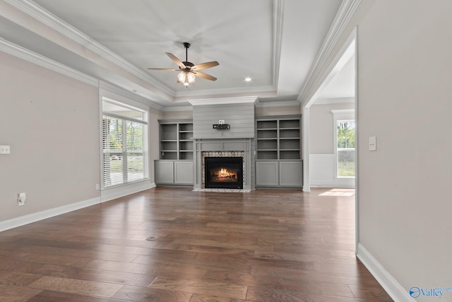 unfurnished living room with dark wood-type flooring, ceiling fan, a high end fireplace, and a healthy amount of sunlight