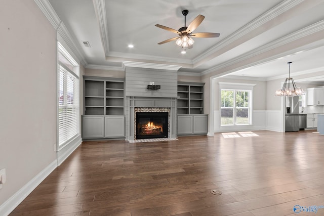 unfurnished living room featuring visible vents, dark wood finished floors, crown molding, ceiling fan with notable chandelier, and a premium fireplace