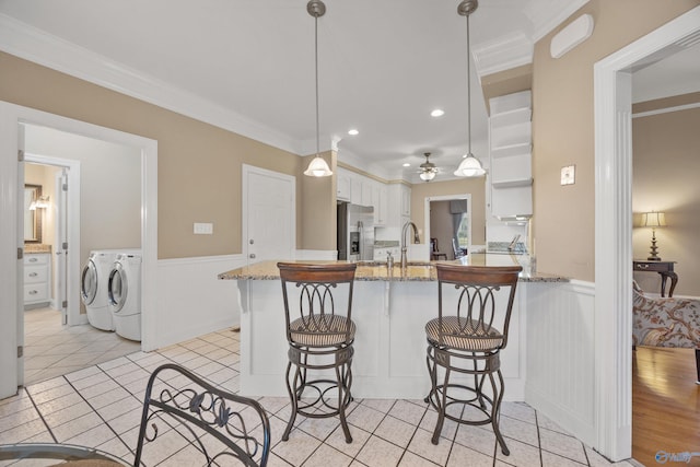 kitchen with white cabinetry, pendant lighting, stainless steel refrigerator with ice dispenser, kitchen peninsula, and independent washer and dryer