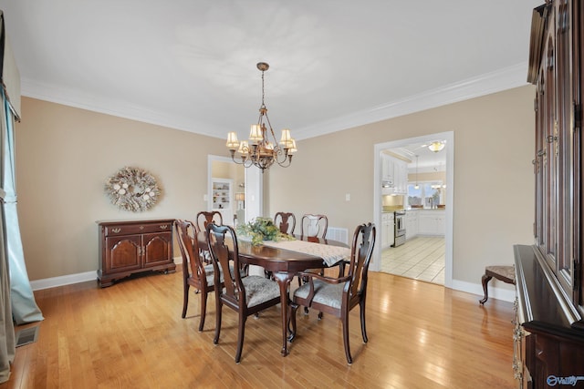 dining space featuring light hardwood / wood-style floors, a chandelier, and crown molding