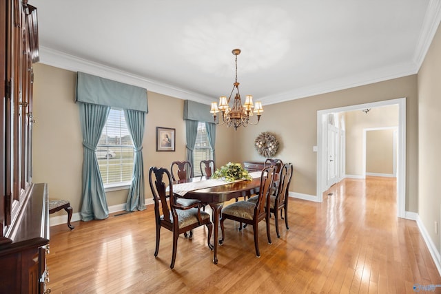 dining room with a chandelier, light wood-type flooring, and ornamental molding