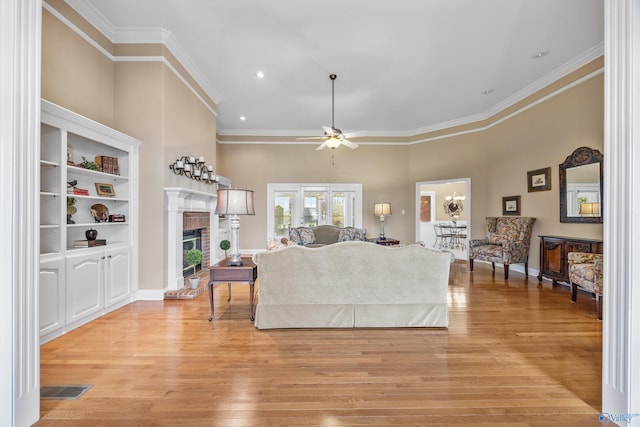 living room with ornamental molding, light wood-type flooring, ceiling fan, and a fireplace