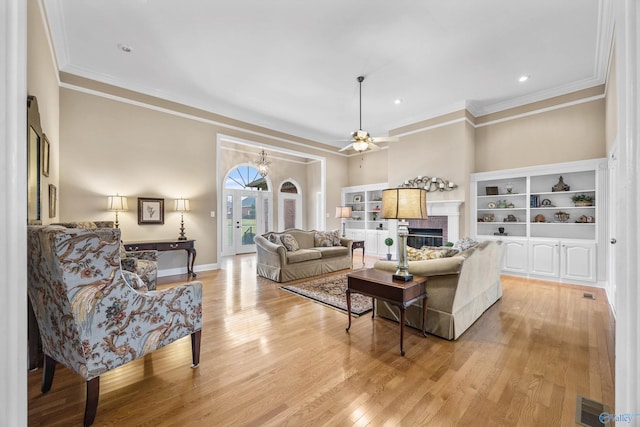 living room featuring a fireplace, ceiling fan, light hardwood / wood-style flooring, and ornamental molding