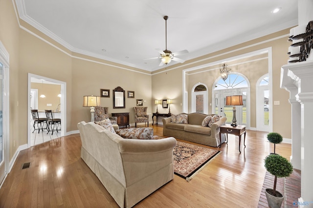 living room featuring ornamental molding, ceiling fan with notable chandelier, and light hardwood / wood-style floors