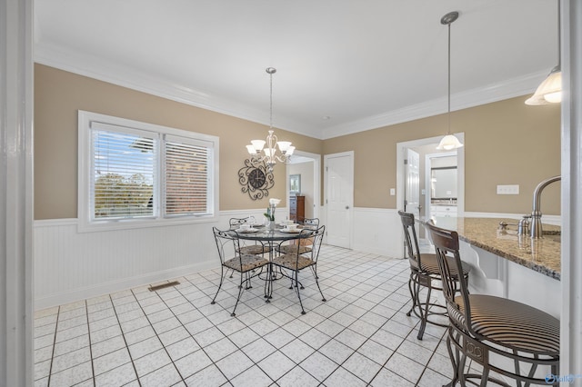 dining area featuring sink, an inviting chandelier, and ornamental molding