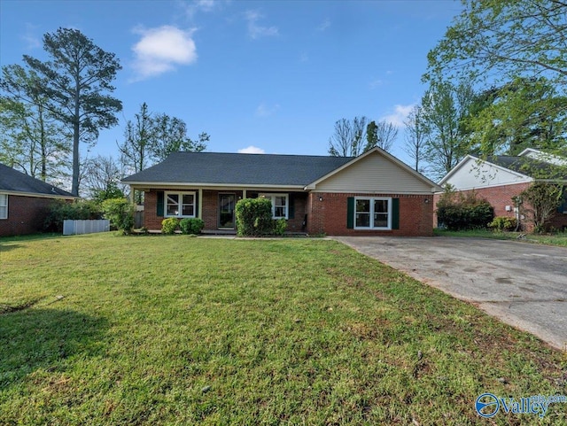 single story home with concrete driveway, a front yard, fence, and brick siding