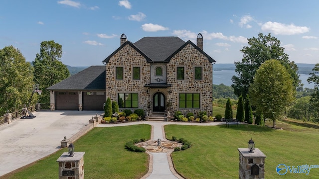 view of front facade featuring a garage, a water view, a front lawn, and a trampoline