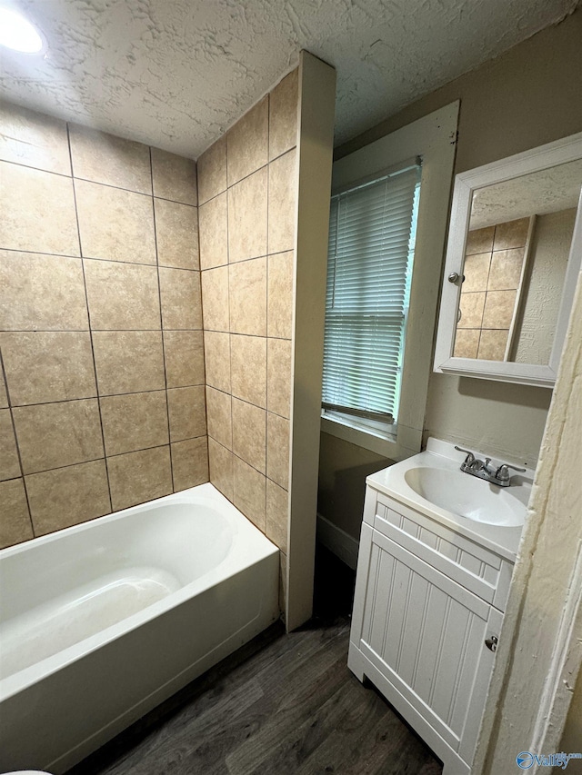 bathroom featuring a textured ceiling, a bathing tub, vanity, and wood finished floors