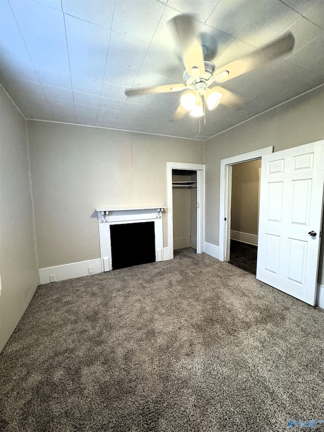 unfurnished bedroom featuring ceiling fan, a fireplace, baseboards, a closet, and carpet flooring