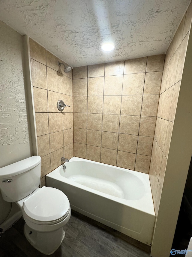 full bath featuring a textured ceiling, toilet, and shower / washtub combination