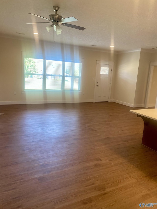 unfurnished living room with baseboards, a ceiling fan, dark wood-type flooring, and ornamental molding