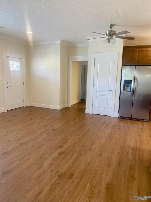 unfurnished living room with baseboards, ceiling fan, crown molding, a textured ceiling, and light wood-style floors