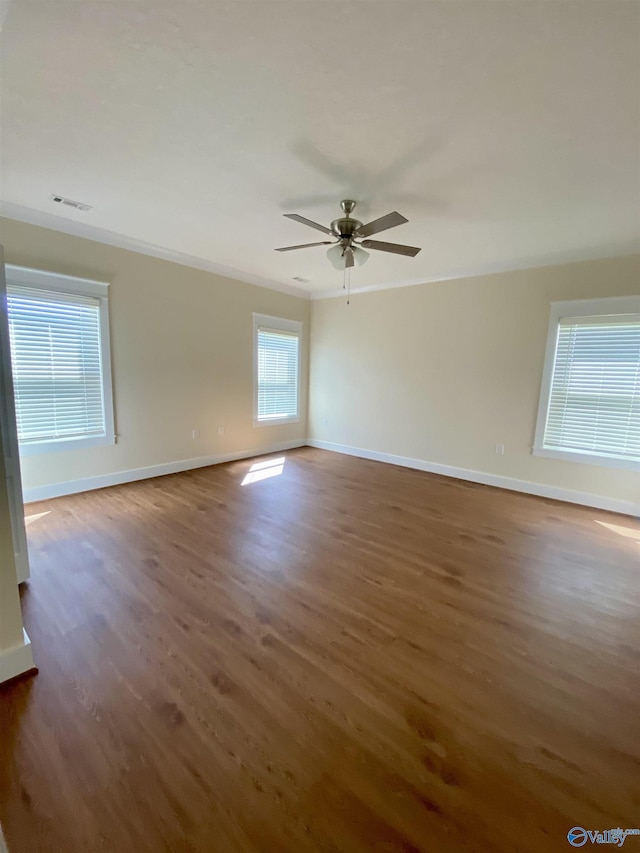 unfurnished room featuring a ceiling fan, crown molding, baseboards, and wood finished floors