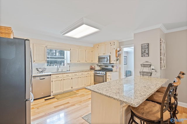 kitchen with stainless steel appliances, light hardwood / wood-style floors, a kitchen breakfast bar, sink, and light stone counters