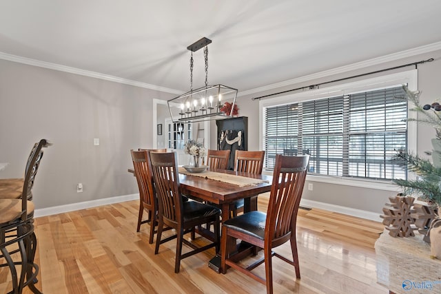 dining space with light wood-type flooring, a notable chandelier, and ornamental molding