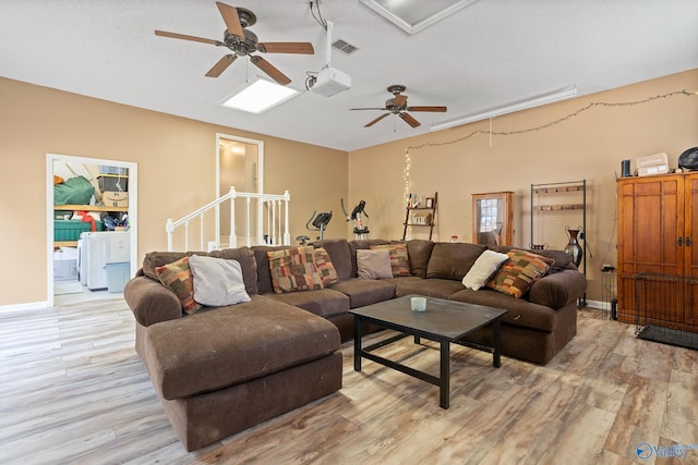 living room with ceiling fan, a textured ceiling, and light wood-type flooring