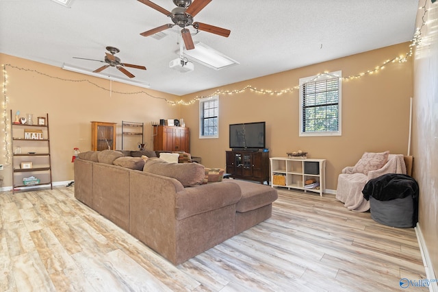 living room featuring ceiling fan, light hardwood / wood-style floors, and a textured ceiling