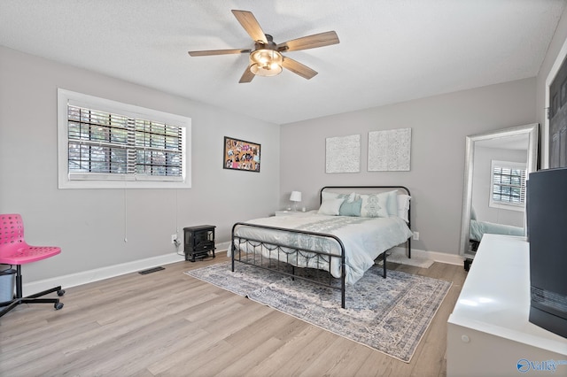 bedroom with ceiling fan, light hardwood / wood-style flooring, and a textured ceiling