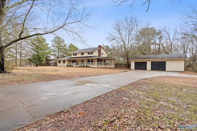 view of front of property featuring a garage, covered porch, and an outbuilding